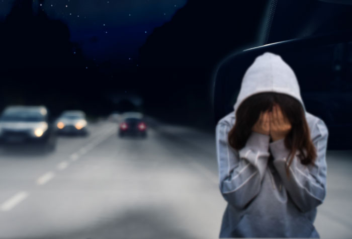 בחורה מכסה פנים בידיים בחושך על הכביש