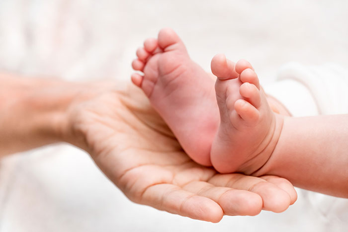 יד מחזיקה רגליים קטנות של תינוק