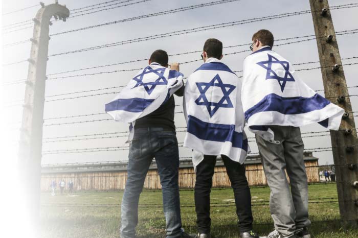 בחורים עטופים בדגל ישראל מול גדרות תיל
