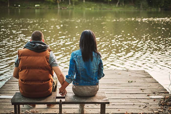 זוג יושב ליד נהר ונותן ידיים