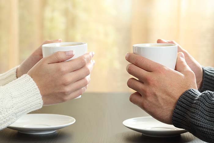 2 זוגות ידיים מחזיקות קפה אחד מול השני