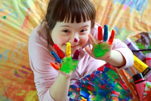 ילדה עם ידיים צבעוניות מגואש עם תסמונת דאון